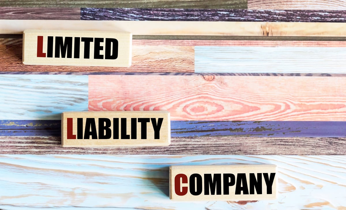 LLC is the text of a limited liability company on wooden blocks on a beautiful background. A concept in finance and economics.